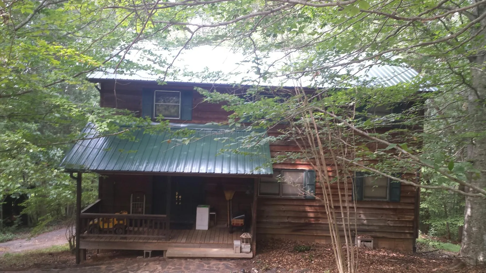 Green metal roof and covered porch on a log cabin in Boiling Springs