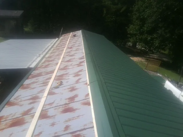 Old rusted panels beside newly installed green metal roofing — Wind Damage Roof Repair by Roofing Brothers in Boiling Springs